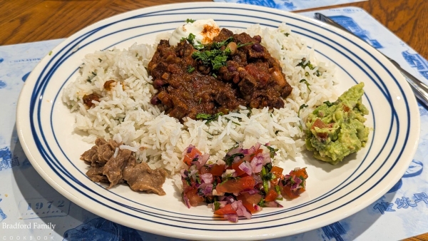 Chilli con carne on a bed of Mexican rice with refried beans, a fresh tomato salsa and home-made guacamole